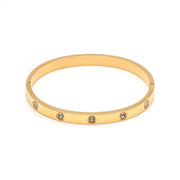 A gold metal bangle studded with cubic zirconia gems.