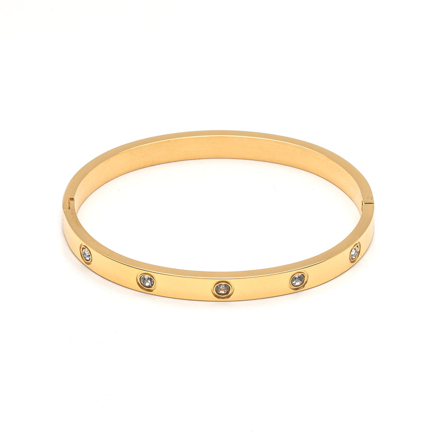 A gold metal bangle studded with cubic zirconia gems.
