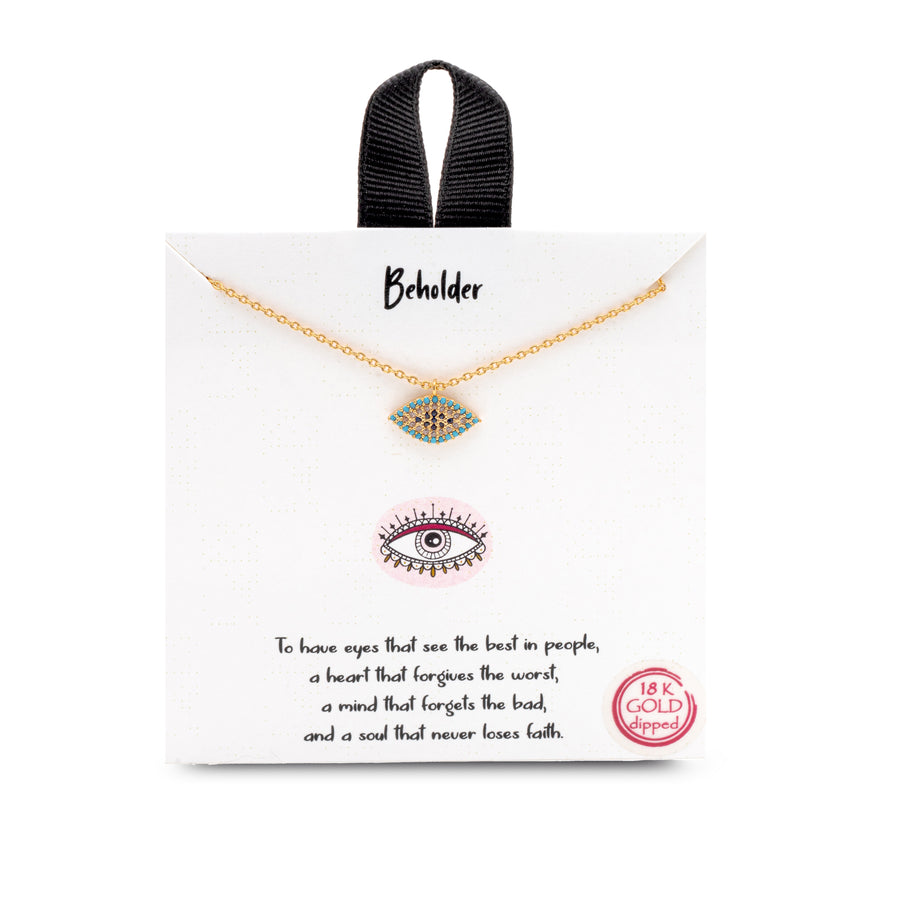 A rhinestone eye charm on a gold chain. The necklace is on a card with text.
