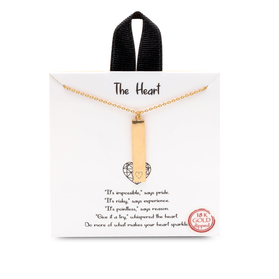 A gold charm necklace. The charm is a vertical bar with a small heart etched on the bottom.
