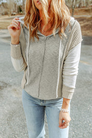 A light grey knit drawstring hoodie of segmented color blocks. The segments are the torso, shoulders and side seams, sleeves, and cuffs.