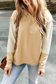 A tan hooded sweatshirt with segmented sleeves. The largest middle segment is of textured off-white fabric.