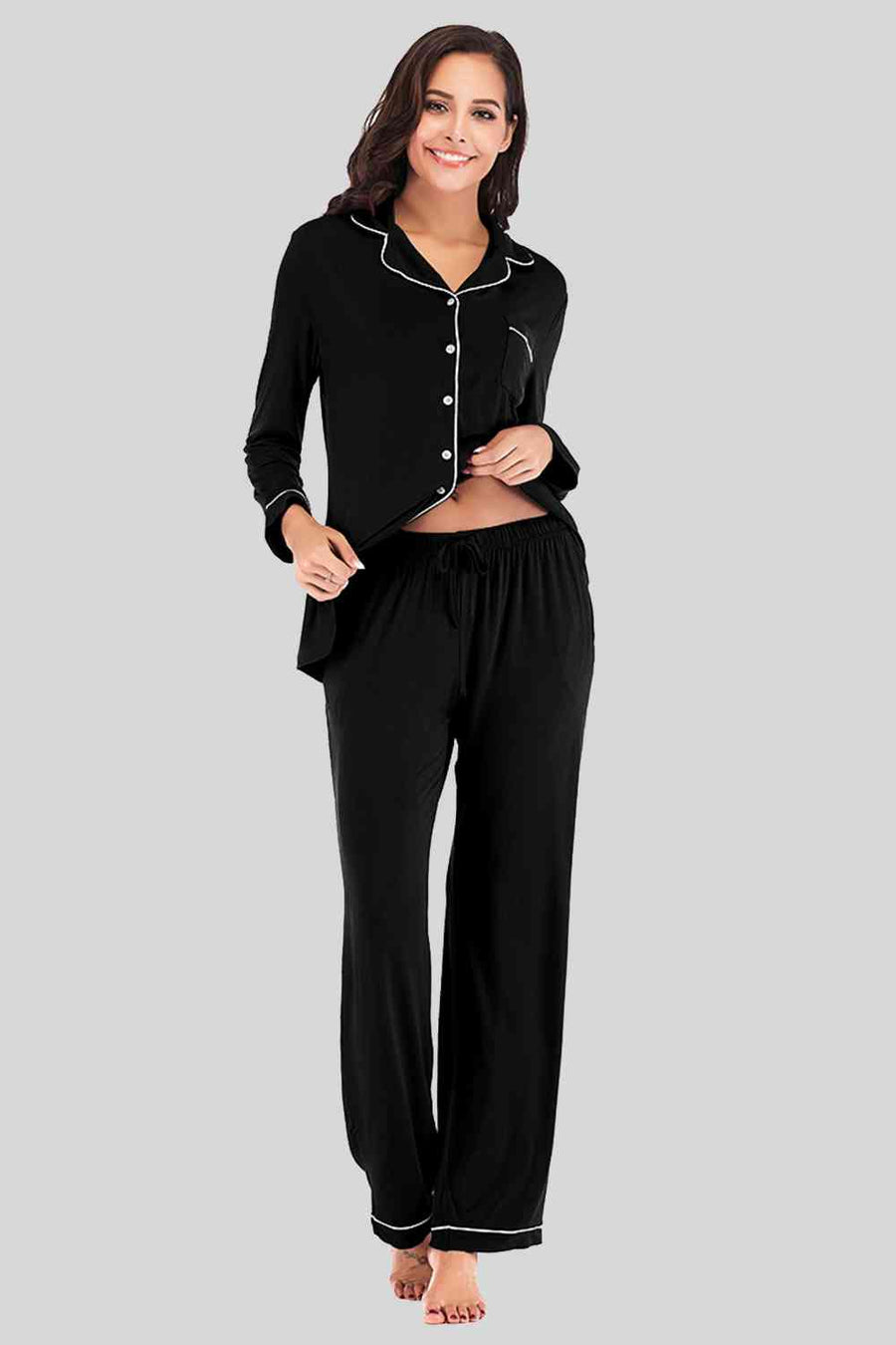 Black pajama pants and button down top. Features white piping and breast pocket.
