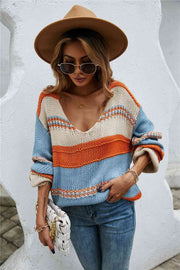 A baggy knit sweater of orange, light blue, and off-white horizontal stripes. The stripes are of varying widths.