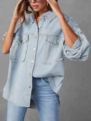A chambray button-down jacket with raw hems on the collar, sleeves, and breast pockets. The pockets have silver studs along the flap. The buttons are flat silver.
