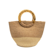 A mid-size, round-bottom straw bag with round Lucite handles. The top half of the bag is natural straw, while the bottom half has a metallic gold finish.