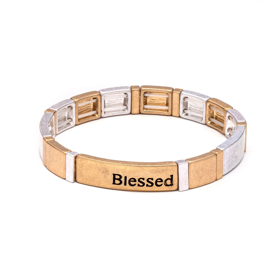 A stretch bracelet of gold and silver block beads; the center bead reads "Blessed".