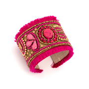 A thick cuff bracelet with pink and gold beaded designs and pink fringe.