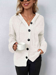 A cream knit sweater with a drawstring hood and large black buttons.