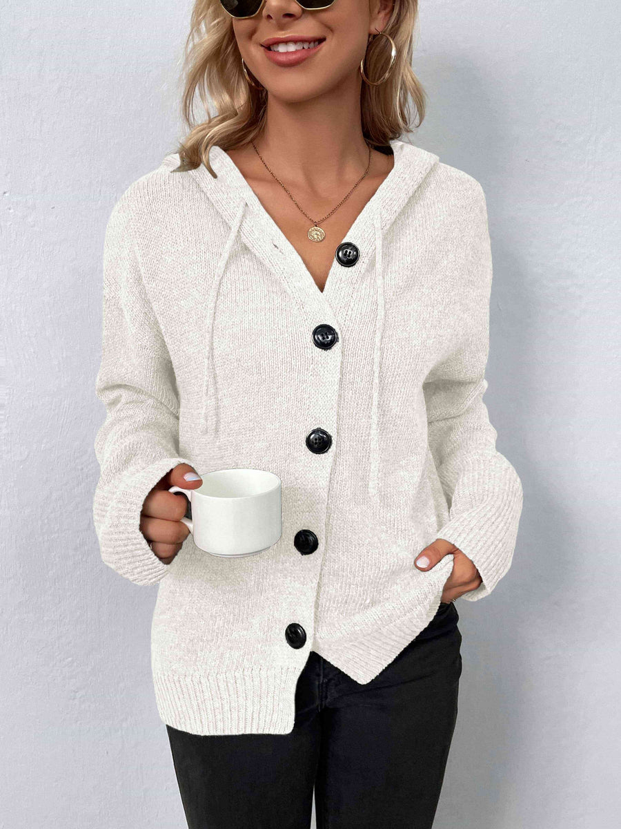A cream knit sweater with a drawstring hood and large black buttons.