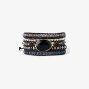 A bracelet made of five bands of gray, black, or silver beads, with a large black gem in the center.