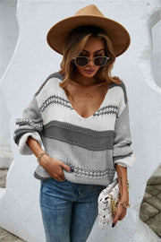 A baggy knit sweater of charcoal, grey, and white horizontal stripes. The stripes are of varying widths.