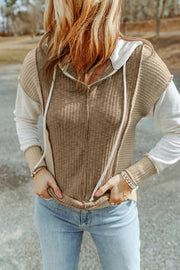 A tan knit drawstring hoodie of segmented color blocks. The segments are the torso, shoulders and side seams, sleeves, and cuffs.