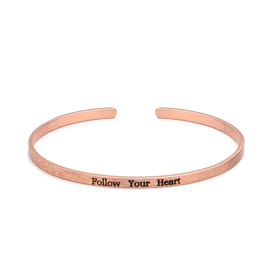 Encouraging sentiment Brass "Follow Your Heart" Slim Cuff Bracelet in rose gold with text inscribed in black lettering on white background