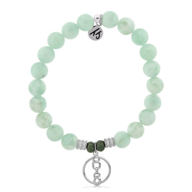 A T. Jazelle bracelet with a round, silver charm with three chainlinks in the center and light green stone beads.