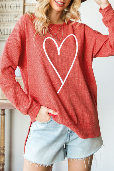Red sweater with large white heart outline graphic. Long sleeve, upper-thigh length, slit sides from bottom hem to hip.