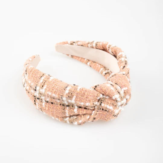 A wide headband wrapped in blush pink tweed with a stylized knot at the top.
