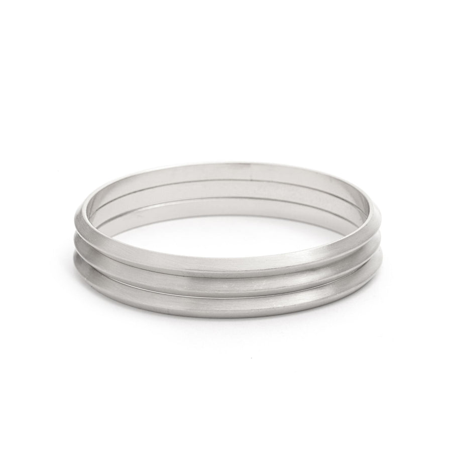 Satin Set of three Bangle Bracelets in matte silver stacked on one another on white background